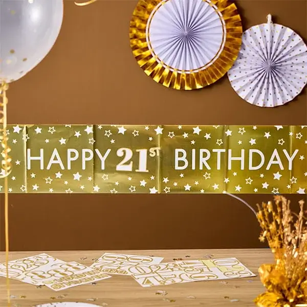 Gold 21st birthday banner with hanging paper decorations, balloons, and matching gold party décor.